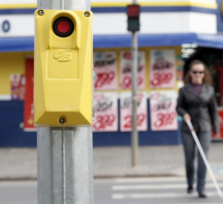 Mulher cega atravessando a rua. Em foco, uma botoeira. Mulher cega atravessando a rua. Em foco, uma botoeira.