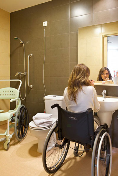 Foto de um banheiro adequado: sem box, com cadeira de banho, barra de apoio e espaço livre embaixo da pia.